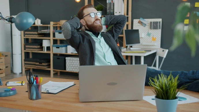 Man relaxing at his office desk with laptop